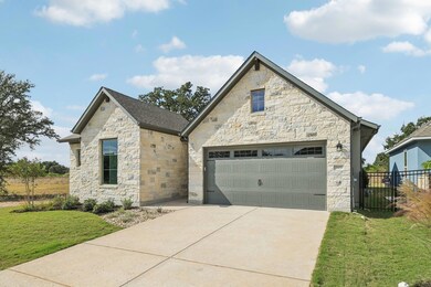 French country home with stone siding, a garage, and concrete driveway