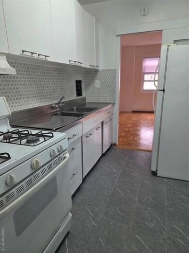 Kitchen featuring stove, fridge, white cabinetry, backsplash, and dark countertops