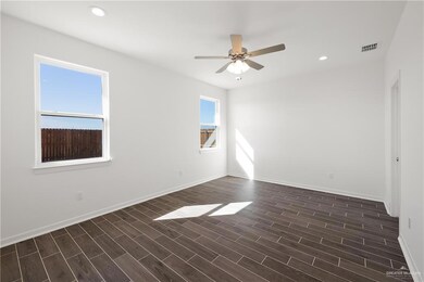Empty room with dark wood-style floors, baseboards, visible vents, and recessed lighting