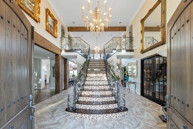 Entryway featuring french doors, a chandelier, a high ceiling, stairway, and crown molding