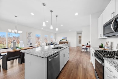 Kitchen featuring stainless steel appliances, white cabinets, light stone countertops, and recessed lighting