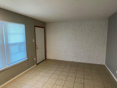 Unfurnished room featuring baseboards, brick wall,