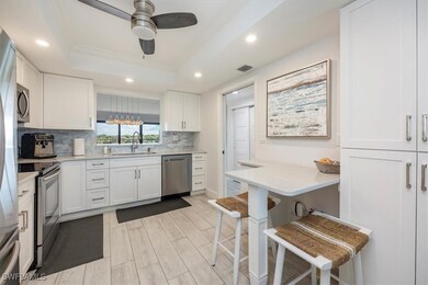 Kitchen with white cabinets, a tray ceiling, stainless steel appliances, and recessed lighting