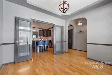 Dining room featuring arched walkways, light wood-type flooring, a chandelier, and a tray ceiling
