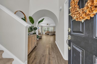 Foyer entrance with wood finished floors, a ceiling fan, baseboards, and stairs