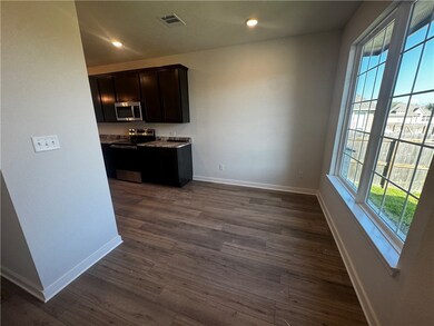 Kitchen featuring stainless steel appliances, dark brown cabinetry, dark wood-style floors, recessed lighting, and light stone counters