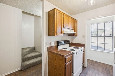 Kitchen featuring white electric range, dark countertops, dark wood finished floors, a textured ceiling, and under cabinet range hood