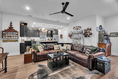 Living area featuring a ceiling fan, light wood-style flooring, and recessed lighting