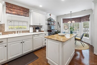 Kitchen with tasteful backsplash, white cabinets,