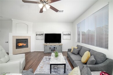 Living room featuring a ceiling fan, dark wood-typ