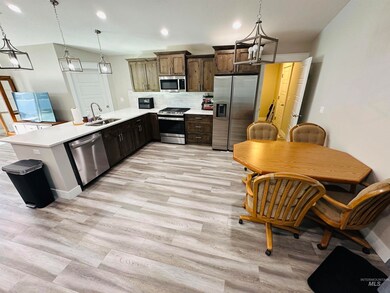 Kitchen featuring stainless steel appliances, decorative light fixtures, backsplash, a peninsula, and light wood-type flooring