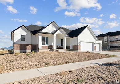 View of front of home with brick siding, covered porch, a garage, and concrete driveway