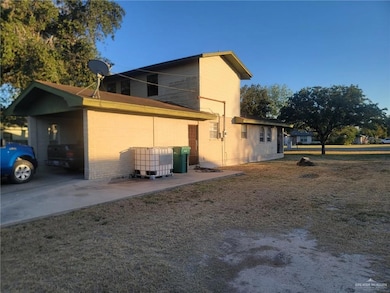 View of side of home with a carport, brick siding, and a yard