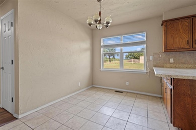Unfurnished dining area featuring a textured wall, light tile patterned floors, a chandelier, and a textured ceiling