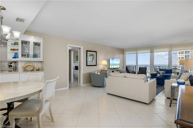 Living room featuring expansive windows, light tile patterned flooring, sink, and a notable chandelier