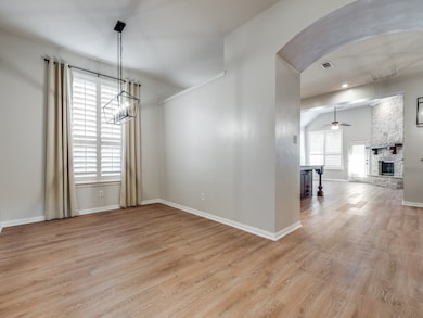 Unfurnished dining area featuring arched walkways, light wood-type flooring, a fireplace, and a ceiling fan