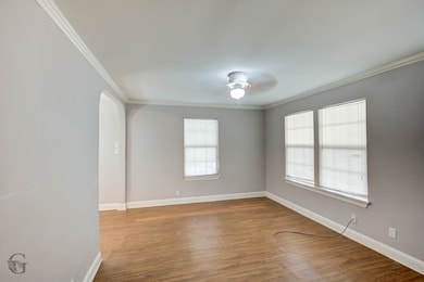 Spare room featuring ornamental molding, arched walkways, light wood-style floors, and ceiling fan