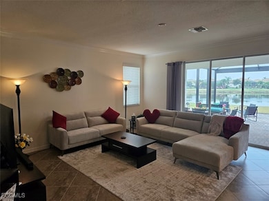 Living room with crown molding, a water view, dark tile patterned flooring, and a textured ceiling