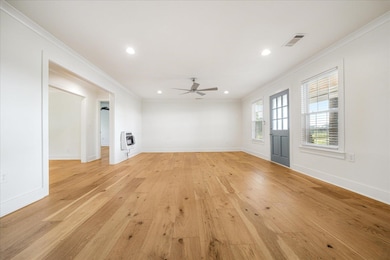 Unfurnished living room featuring heating unit, ornamental molding, ceiling fan, light wood-style floors, and recessed lighting