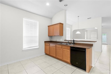 Kitchen with decorative light fixtures, black dishwasher, sink, and kitchen peninsula