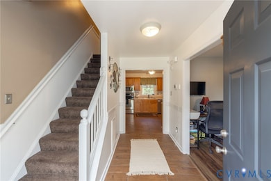 Entryway with dark wood-style flooring, stairs, and a wainscoted wall