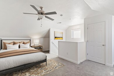 Carpeted bedroom with lofted ceiling, a textured ceiling, and ceiling fan. Staged