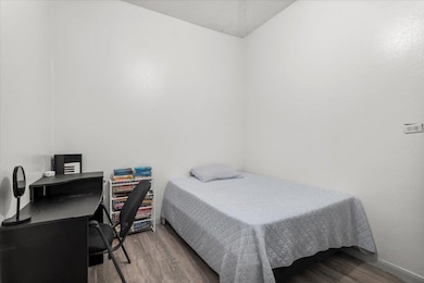 Bedroom with wood finished floors and an office a