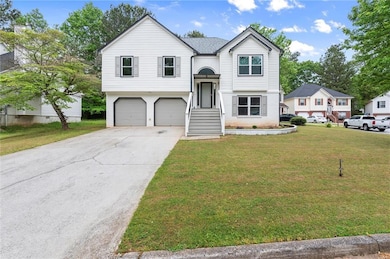 Raised ranch with concrete driveway, a front yard,