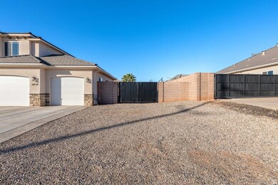 View of side of property with stucco siding, a gate, stone siding, and concrete driveway