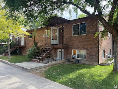 View of front of Triplex with brick siding, a front yard, and stairway