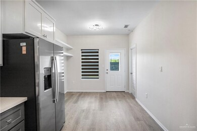 Kitchen with visible vents, stainless steel fridge, light countertops, white cabinetry, and light wood finished floors