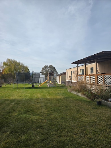 View of grassy yard featuring a playground and a trampoline