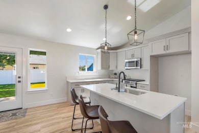 Kitchen featuring lofted ceiling, light wood-type flooring, a kitchen island with sink, appliances with stainless steel finishes, and recessed lighting