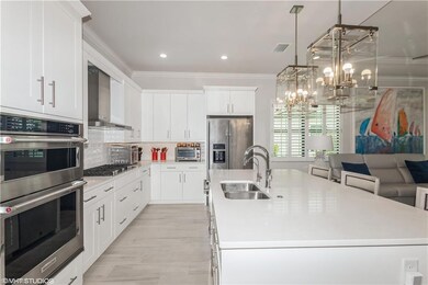 Kitchen featuring wall chimney exhaust hood, a sink, stainless steel appliances, ornamental molding, and a center island with sink