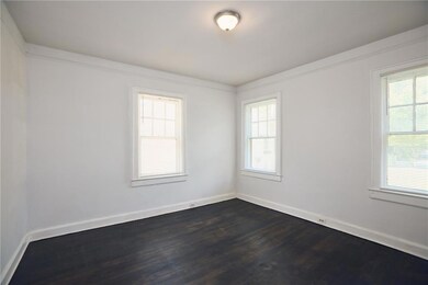 Spare room with dark wood-type flooring and baseboards