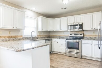 Kitchen featuring a peninsula, white cabinetry, vi