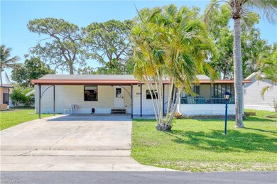 View of front of house featuring concrete driveway, an attached carport, a front lawn, and a sunroom