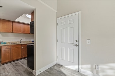 Kitchen featuring brown cabinetry, light wood-style floors, and light stone countertops