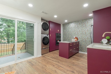 Washroom featuring stacked washing machine and dryer, light wood-style floors, recessed lighting, and wallpapered walls