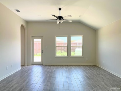 Unfurnished living room with a ceiling fan, wood finished floors, arched walkways, and vaulted ceiling