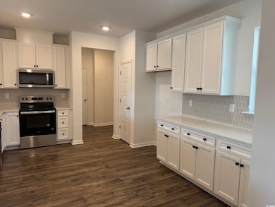 Kitchen featuring white cabinetry, tasteful backsp