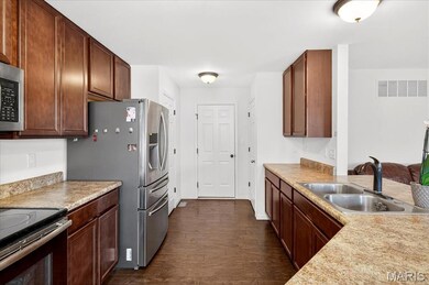 Kitchen with dark wood-type flooring, appliances with stainless steel finishes, and light countertops