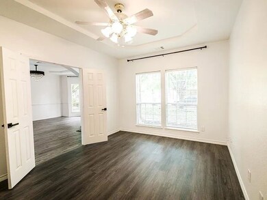 Spare room featuring plenty of natural light, dark wood-style flooring, ceiling fan, and a chandelier