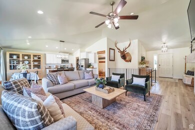 Living room with lofted ceiling, light wood-style flooring, a chandelier, recessed lighting, and ceiling fan