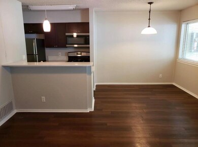 Kitchen featuring stainless steel microwave, freestanding refrigerator, dark wood-style floors, range, and a textured ceiling