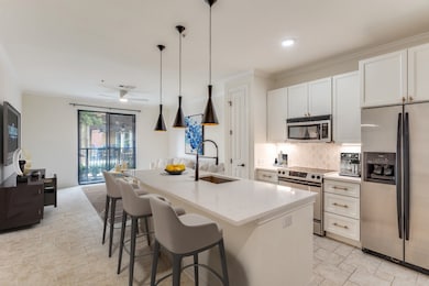 Kitchen featuring appliances with stainless steel finishes, tasteful backsplash, ornamental molding, white cabinetry, and a kitchen bar