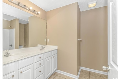 Full bathroom featuring tile patterned floors, baseboards, double vanity, and a shower