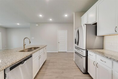 Kitchen featuring appliances with stainless steel finishes, granite countertops, light hardwood / wood-style floors, white cabinetry, and sink