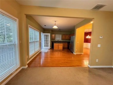 Kitchen with dark countertops, open floor plan, brown cabinets, light carpet, and stainless steel refrigerator with ice dispenser