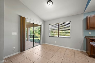 Unfurnished dining area with vaulted ceiling, healthy amount of natural light, and light tile patterned floors